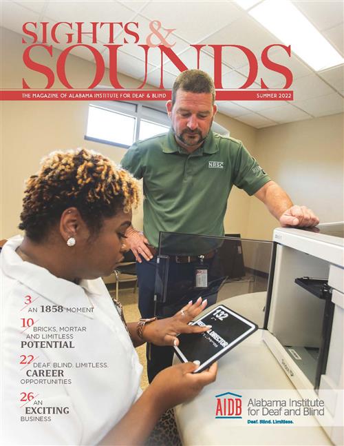 Cover of Sights and Sounds. An instructor stands looking down at a workshop participants who is reading a tactile sign.