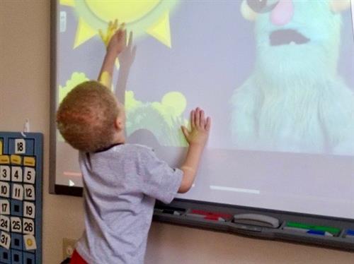 Young boy interacting with screen picture of the sun 