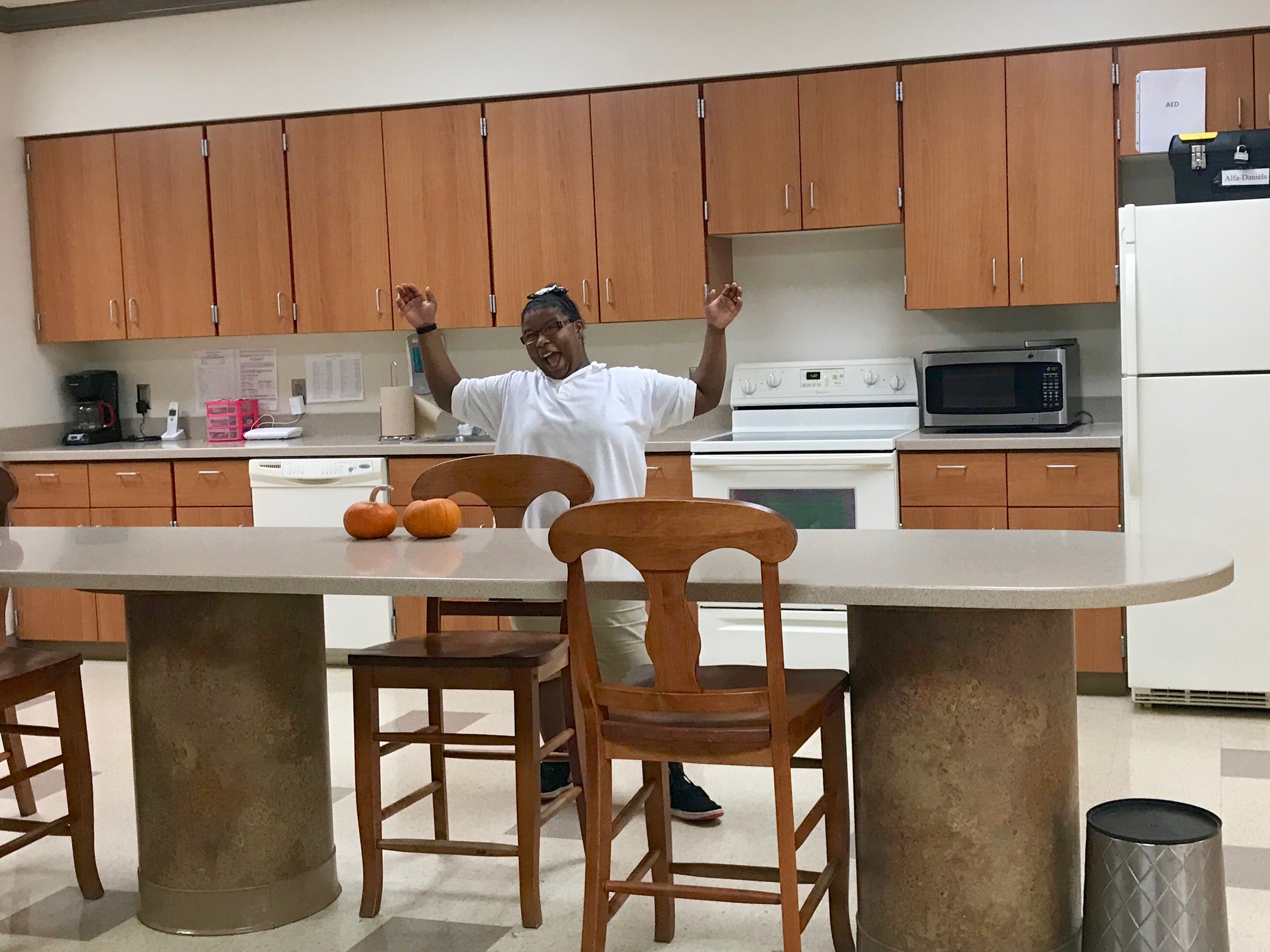 Female student outstretches arms, showing large new kitchen 