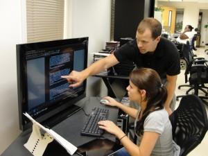 Matt Kochie, of AIDB IT, works with Chelsae at a computer with a screen for VI students at EHG 