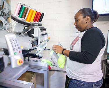 An AIB employee programs an embroidery machine 