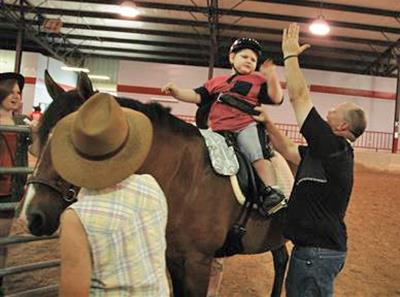 A volunteer gives a student on horseback at the MGHSE arena a high five. 