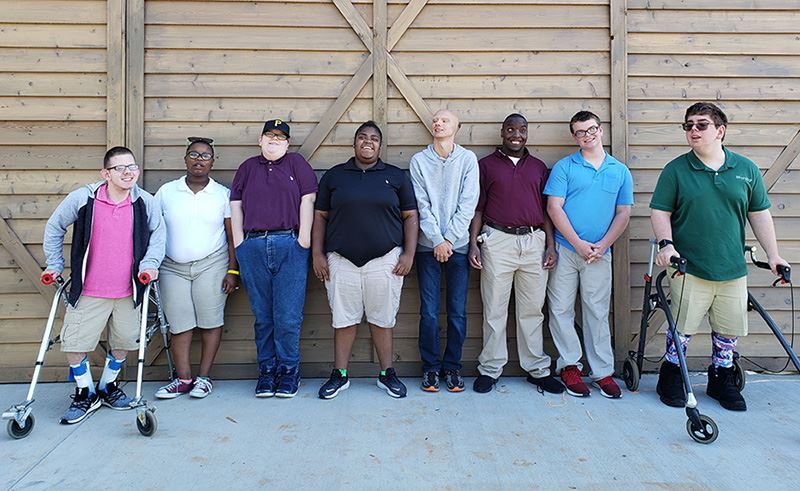 A group of AIDB students stand in front of the barn door of the new JTA Agriscience Center