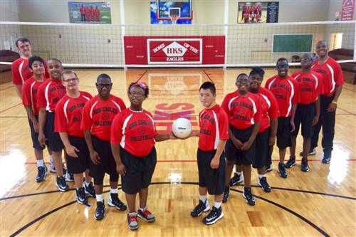 Volleyball team posing in front of the net 