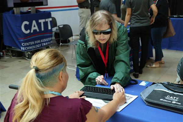 Trainer Jill Dunaway showcasing an AT device to a conference attendee