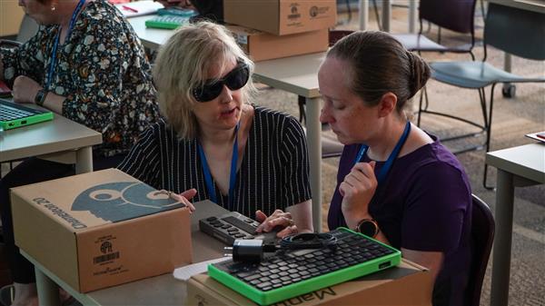 Seated, Jill Dunaway shows an educator how to use the Chameleon 20.