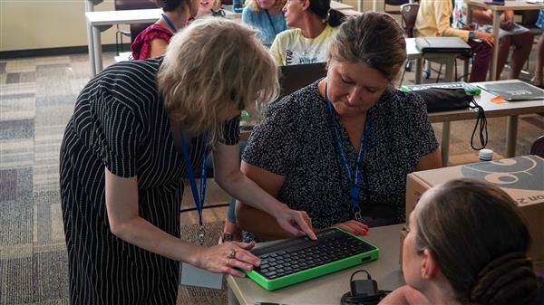 Standing next to a seated attendee, Jill Dunaway shows an educator how to use the Mantis.