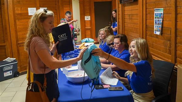 Seated behind a table, CATT faculty are helping educators get registered and settled in at a conference.