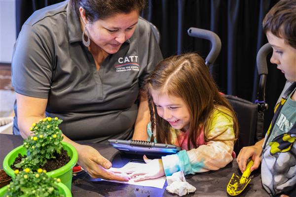Trainer Jennifer Oldenburg shows a young girl something through the APH magnifier