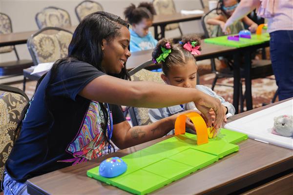 A mom and her young daughter playing with the code and go mouse