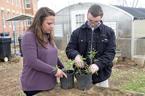Agriscience teacher works on potting flowers with a student