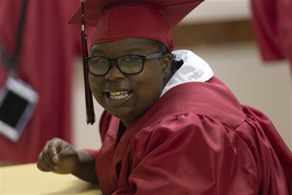 A 2023 graduate from Helen Keller School of Alabama smiles to camera.