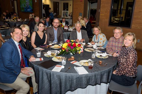 Eight people are sitting around a table smiling at the camera.