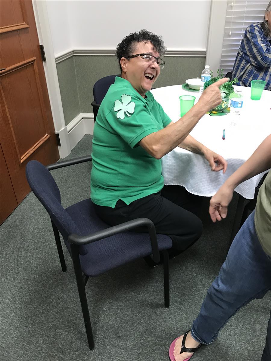 A consumer, seated, laughs and points at something off screen.