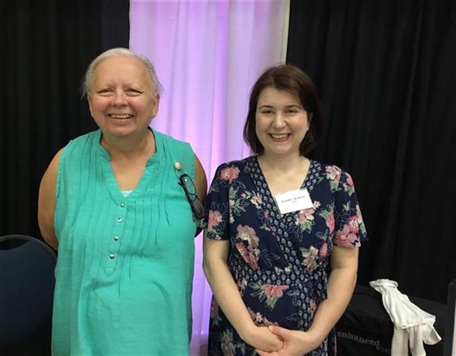 Two women smile to camera.